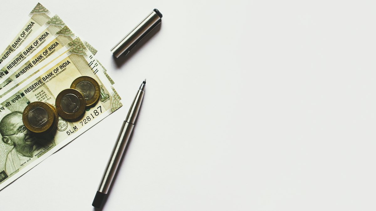 Rupee notes, coins and a pen
