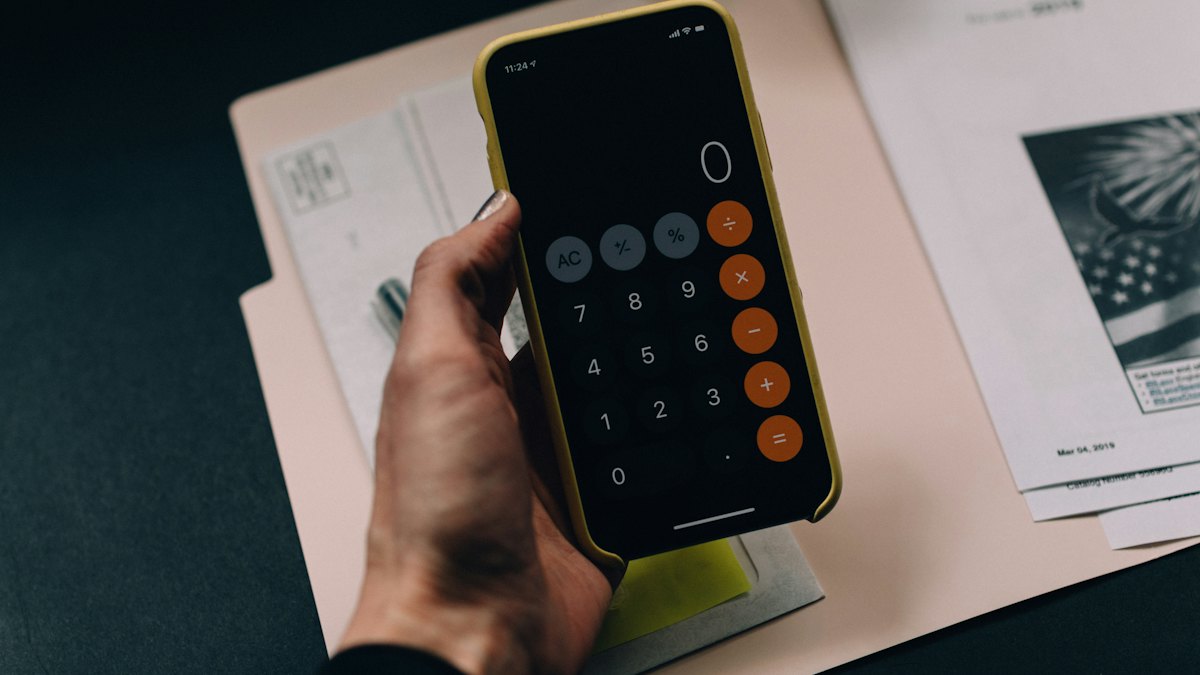 A hand using a calculator on a desk